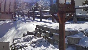 A wooden birdhouse with a snow-covered roof, set against a backdrop of a clear blue sky and a snow-covered mountain. - Amedee Appartement/Fewo 5-Bettwohnung Nr. 1 by Interhome (Saas-Fee)