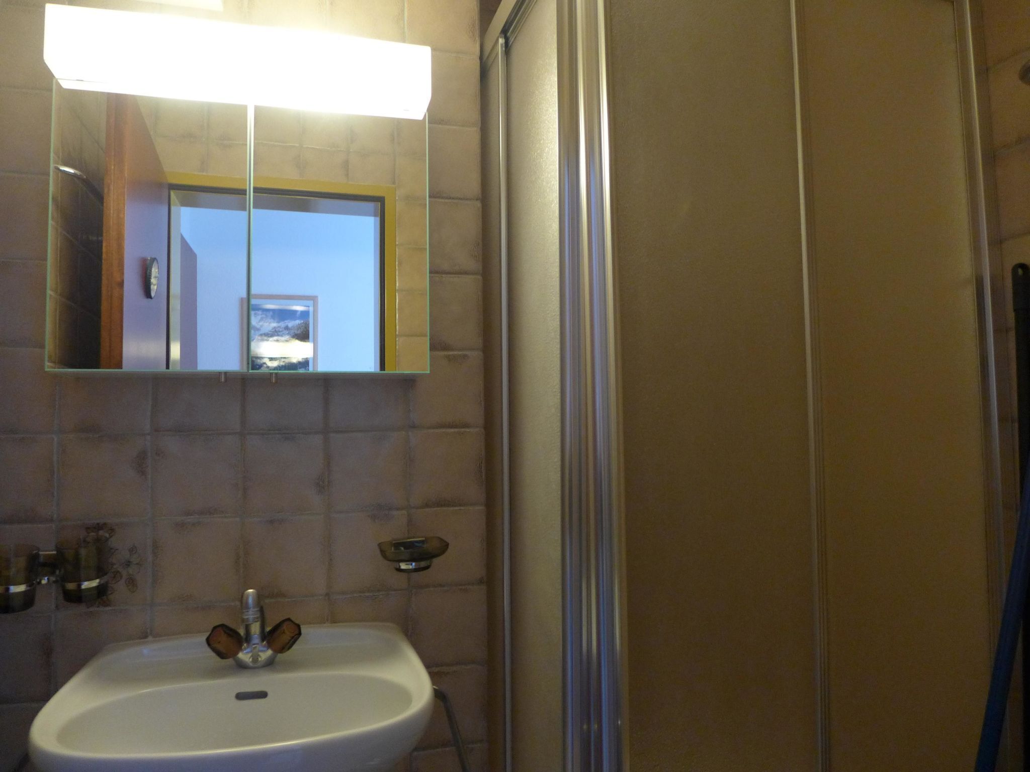 A bathroom with a sink, mirror, and shower.