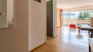 En modern inredning med trägolv, en röd soffa och en matplats med bord och stolar.