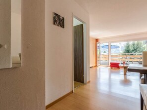 A modern interior with a wooden floor, a red sofa, and a dining area with a table and chairs. - Acimo Appartement/Fewo 2-Bettwohnung Muschi by Interhome (Saas-Fee)