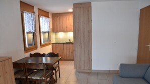 Un ambiente compatto con angolo ristoro, angolo cottura e divano.