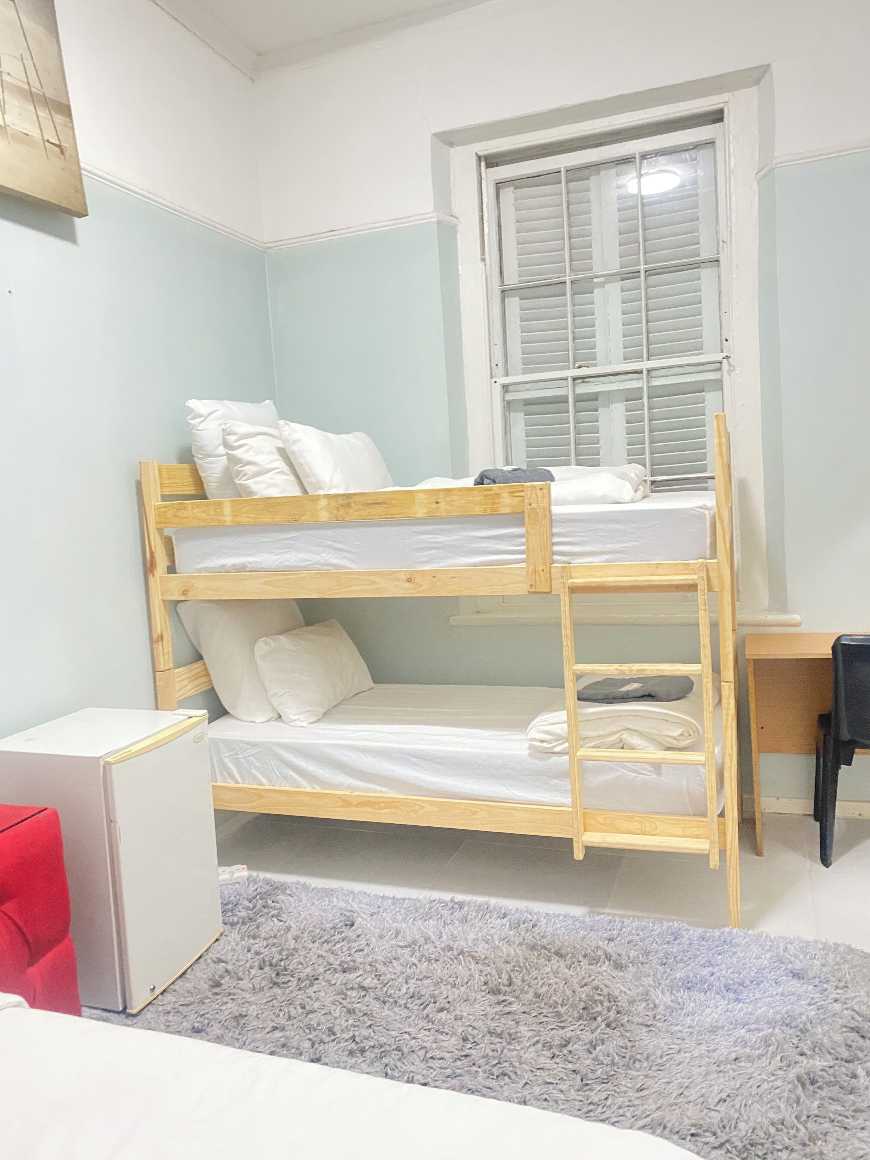 A bunk bed room with a desk and a small refrigerator.