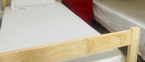 A room with two bunk beds, a red chair, and a wooden nightstand.