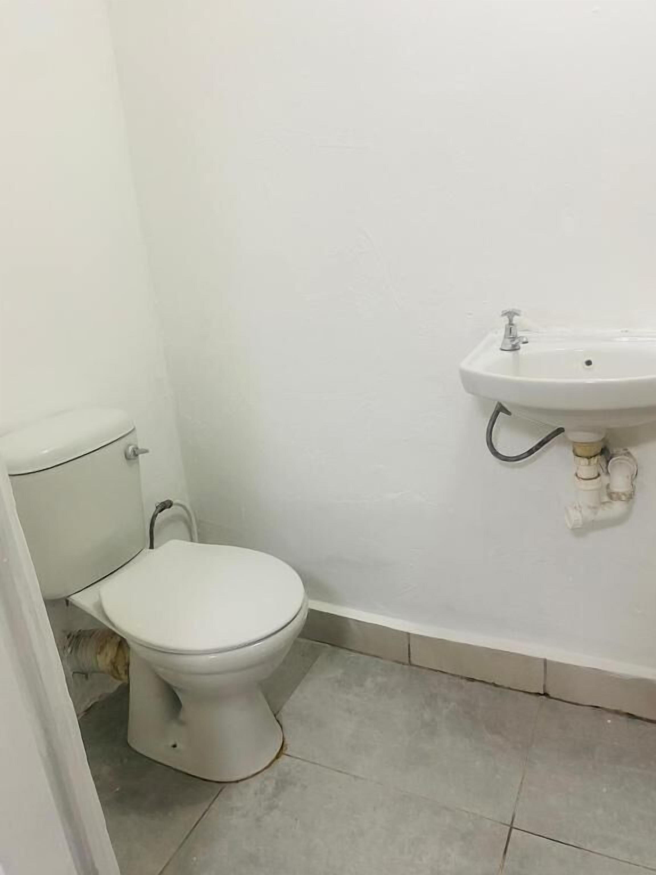 A small bathroom with a toilet, a sink, and a tiled floor.