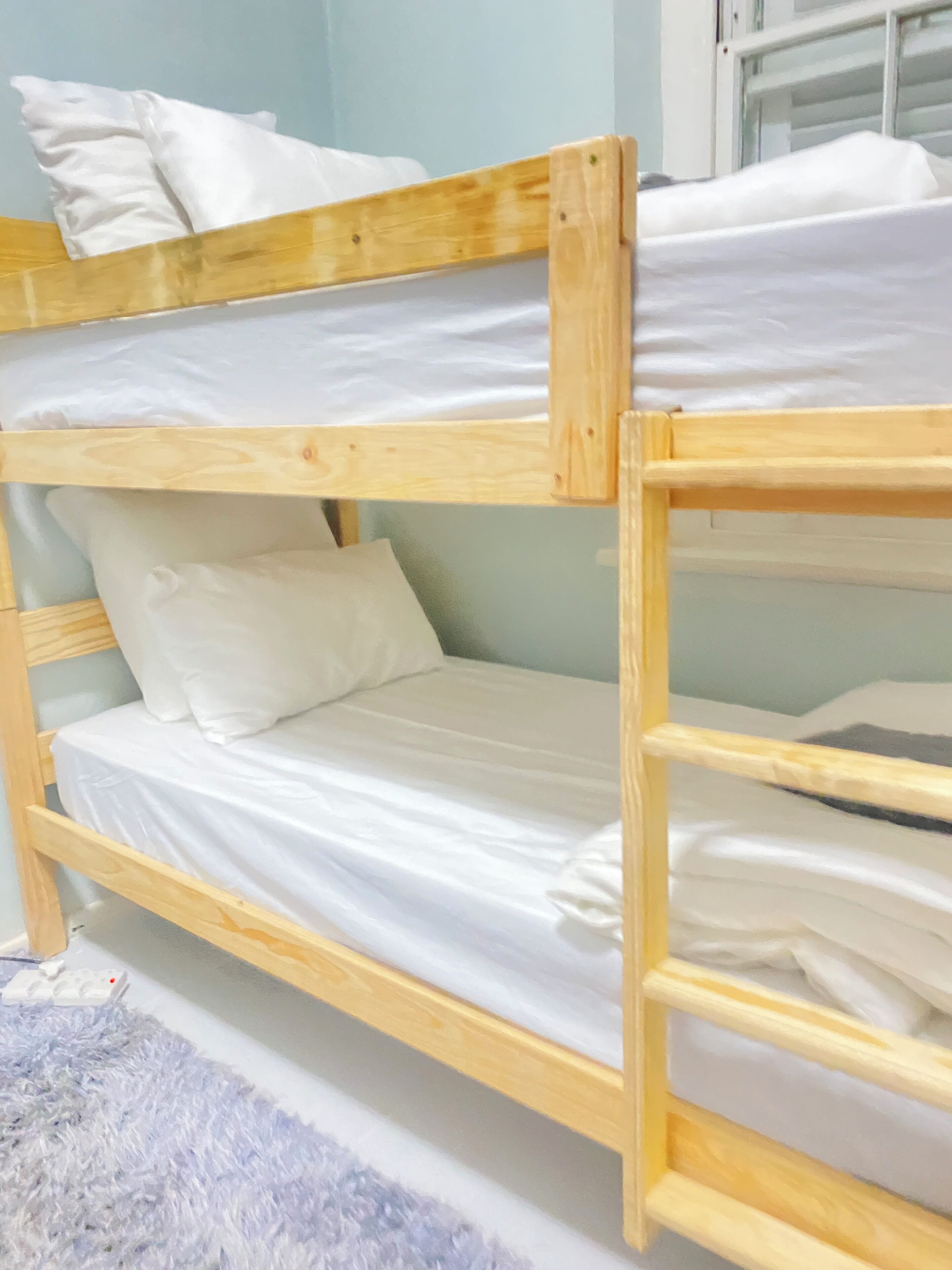 Un lit superposé avec une literie blanche et une structure en bois.
