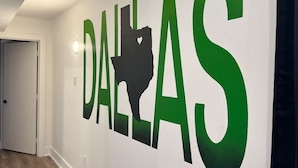 Um corredor com uma placa na parede exibindo a palavra 'DALLAS' em letras grandes e uma silhueta do estado do Texas.