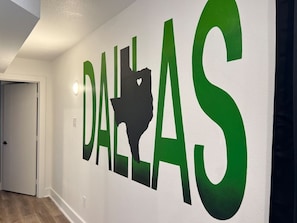 Ein Flur mit einem an der Wand befestigten Schild, das das Wort 'DALLAS' in großen Buchstaben und eine Silhouette des Bundesstaates Texas zeigt.