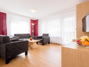 Ein modernes Hotelzimmer mit einer Sofagarnitur, einem Couchtisch und einer Obstschale.