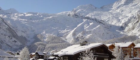 Un pueblo de montaña cubierto de nieve con edificios de madera y cielo despejado.
