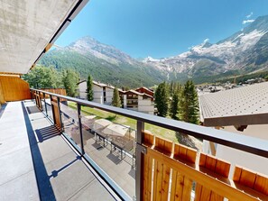 A balcony with a view of a mountainous landscape, wooden buildings, and a clear sky. - Alphubel Peak & Unlimited Appartement/Fewo Unlimited 21 by Interhome (Saas-Fee)