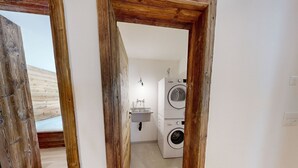 Ein Waschraum mit gestapelten Waschmaschinen und einem Waschbecken.