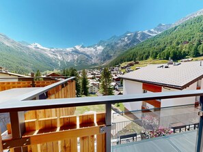 En by belägen i bergen, med hus byggda av trä och utsikt över snöklädda bergstoppar.