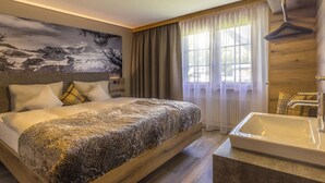 Une chambre d’hôtel moderne dotée d’un grand lit, d’une baignoire et d’une fresque murale représentant un paysage.