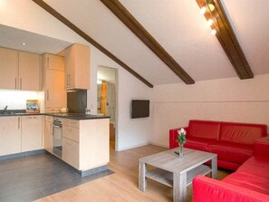 A compact living space with a kitchenette, a red sofa, and a small table with a vase. - Alouette Appartement/Fewo 6-Bettwohnung Nr. 18 by Interhome (Saas-Fee)