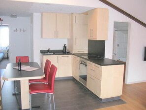 A compact kitchen with a dining area, including a table, chairs, and a built-in oven. - Alouette Appartement/Fewo 6-Bettwohnung Nr. 18 by Interhome (Saas-Fee)