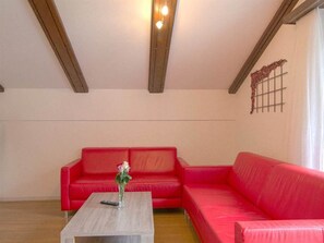 A living room with a red sofa, a wooden coffee table, and a light fixture on the ceiling. - Alouette Appartement/Fewo 6-Bettwohnung Nr. 18 by Interhome (Saas-Fee)