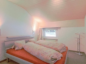 Une petite chambre avec un lit simple, une fenêtre, une table de chevet et un radiateur.