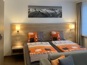 A hotel room with two beds, a wooden headboard, a painting of mountains, and two bedside lamps. - Apartments Arcadia Studio Studio Lagginhorn by Interhome (Saas-Fee)