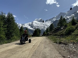 Camí de terra que condueix a una muntanya amb un telefèric al fons.