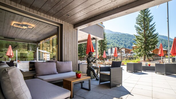 Ein Sitzbereich im Freien mit einer Couch, Stühlen und einer Statue.