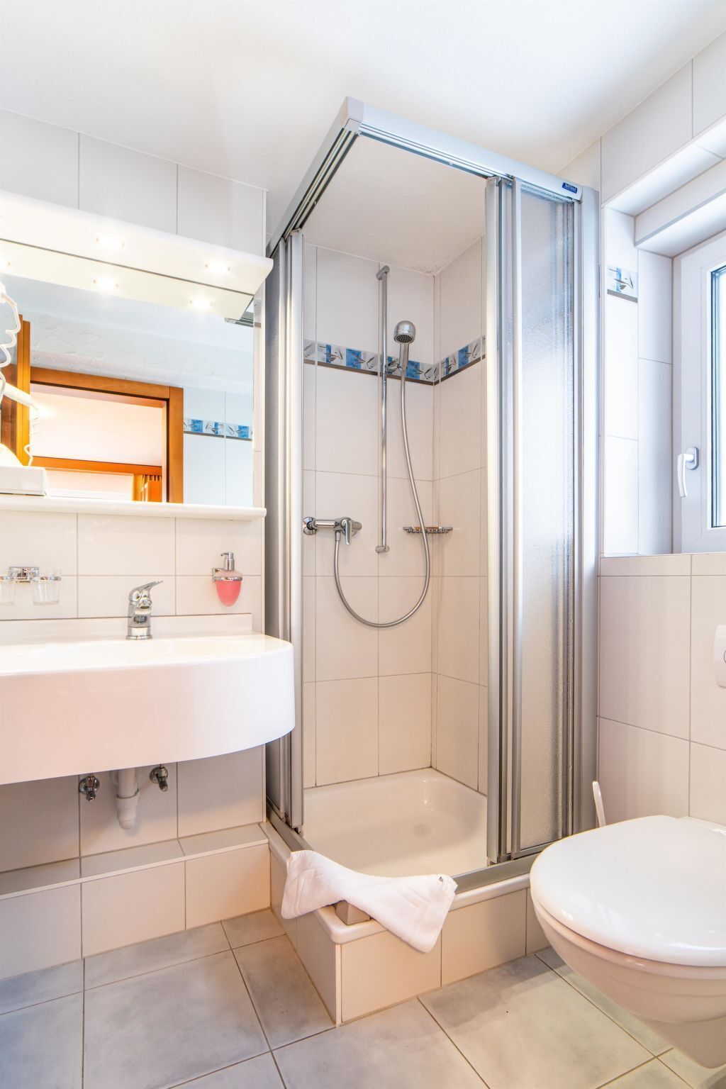 A modern bathroom with a shower enclosure, a sink, and a toilet.