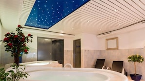 Uma área de spa moderna com hidromassagem, estrelas no teto e plantas em vasos.