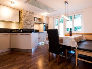 Eine moderne Küche mit Steinwand, Holzboden und einem Essbereich mit Tisch und Stühlen.