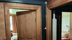 Eine Holztür, die in ein Schlafzimmer mit einem Bett und einem Nachttisch führt.