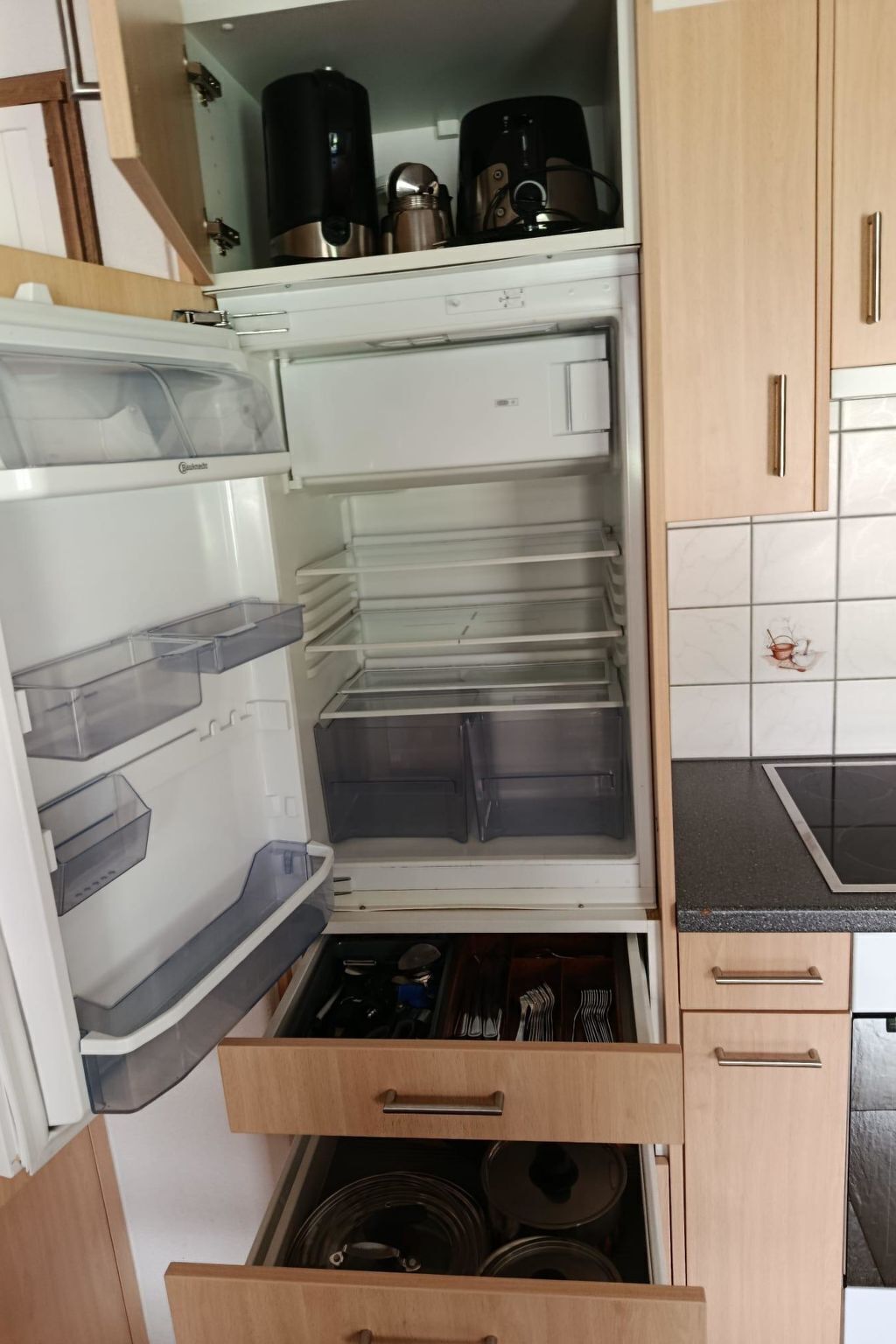 Une cuisine équipée d’un réfrigérateur encastré, d’un four à micro-ondes et d’une cuisinière.