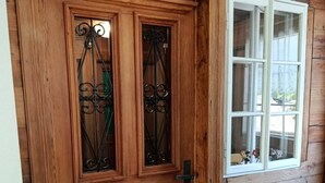 Eine Holztür mit Fensterglas und ein Fenster zur Rechten.
