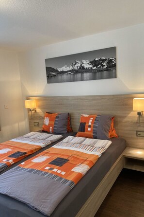 Ein Hotelzimmer mit einem Bett, zwei Nachttischlampen, einem Wandbild und einem Nachttisch.