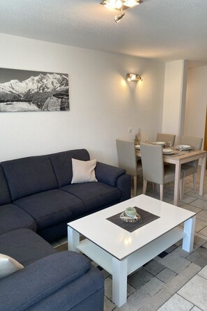 Ein Wohnzimmer mit einer Couch, einem Couchtisch und einem Essbereich mit Stühlen und einem Tisch.
