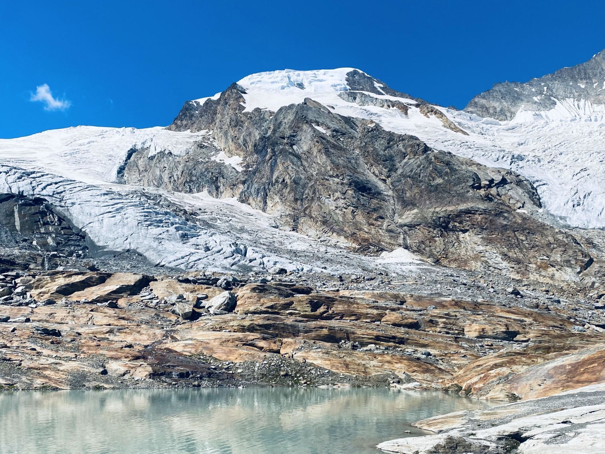 A mountainous landscape with a glacier and a clear lake.