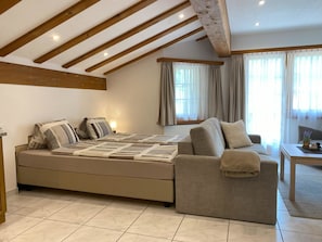 Ein modernes Schlafzimmer mit einem großen Bett, einer Couch und einem Fenster mit Vorhängen.