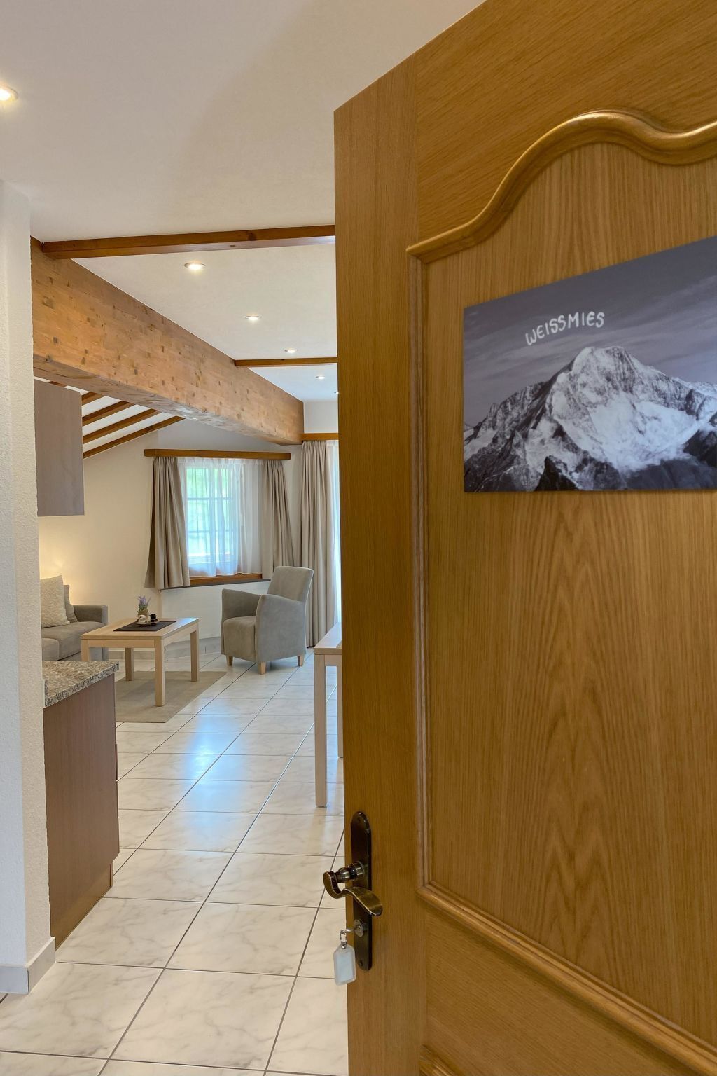 A hotel room with a wooden door, a view of the living area, and a mountain image on the door.