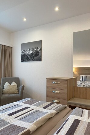 A hotel room with a bed, a chair, a dresser, and a painting on the wall. - Apartments Arcadia Appartement/Fewo 4-Bettwohnung Dom by Interhome (Saas-Grund)