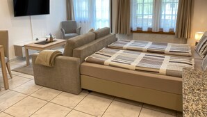 Una sala moderna con sofá, televisión, mesa de comedor y una silla.