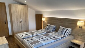 Un dormitorio moderno con una cama grande, un armario de madera, lámparas de noche y una mesita de noche.