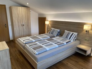 Ein modernes Schlafzimmer mit einem großen Bett, einem Holzschrank, Nachttischlampen und einem Beistelltisch.