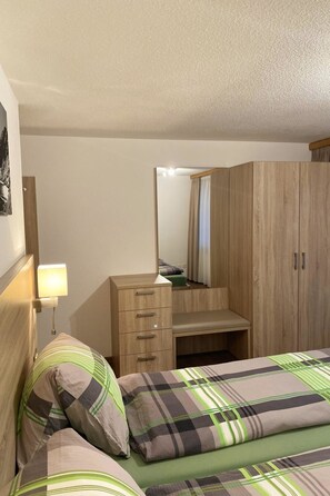 Ein Schlafzimmer mit Bett, Kommode, Spiegel und Nachttisch.