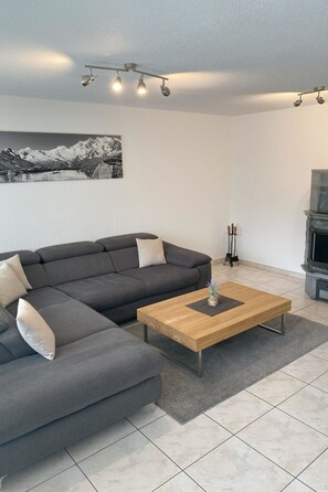 Ein modernes Wohnzimmer mit einem Ecksofa, einem Holztisch und einem Kamin.
