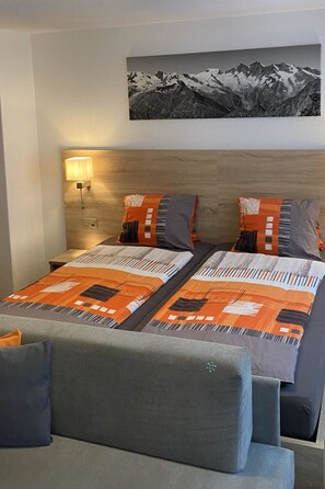 A hotel room with a bed, two pillows, a nightstand, a lamp, and a wall-mounted picture. - Apartments Arcadia Studio Studio Fletschhorn by Interhome (Saas-Grund)