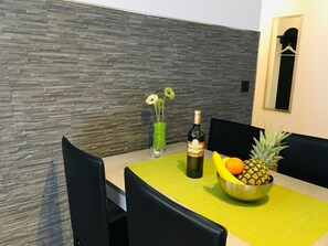 A dining table with a bottle of wine, a bowl of fruit, and a vase with flowers. - Alcazar Apartments Appartement/Fewo Wohnung 2 by Interhome (Saas-Grund)