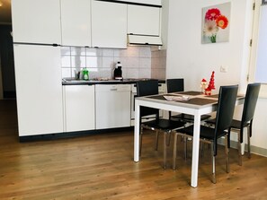 Eine moderne Küche mit weißen Schränken, einem Esstisch mit vier Stühlen und einer kleinen Kücheninsel.