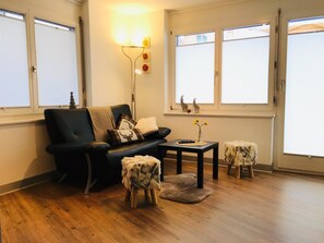Een woonkamer met een bank, een salontafel en twee kleine krukken.