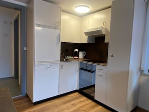 Eine kompakte Küche mit weißen Schränken, einem Backofen und einer Kaffeemaschine.
