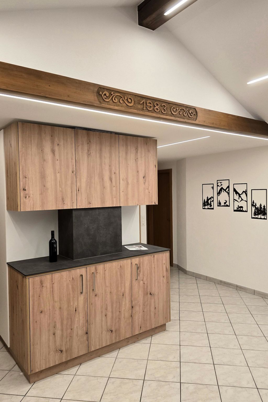 Una cocina con armarios de madera, encimera negra y una lámpara fijada a la pared.