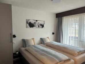 A hotel room with two beds, a wall-mounted artwork, and a window with curtains. - Ferienhaus Alea Appartement/Fewo 4-Bettwohnung Nr. 20 by Interhome (Saas-Grund)
