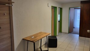 Ein Zimmer mit einem Holztisch, einem schwarzen Hocker und einer grünen Tür.