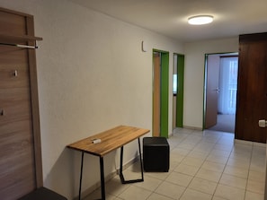 Een kamer met een houten tafel, een zwarte stoel en een groene deur.